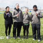 Four Staff members on the soccer field hold up the number 1